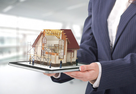 Project concept. Demonstration of an architectural project. Man draws a house project on the tablet.の写真素材