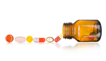 Pills spilling out of pill bottle isolated on white.の写真素材