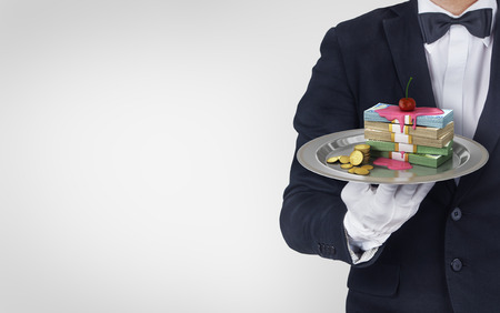Waiter hold restataunt cloche with stack of money poured syrup with a cherry on top. Concept of persent. Money is served!の写真素材