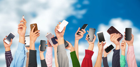 Many hands holding mobile phones against the blue sky