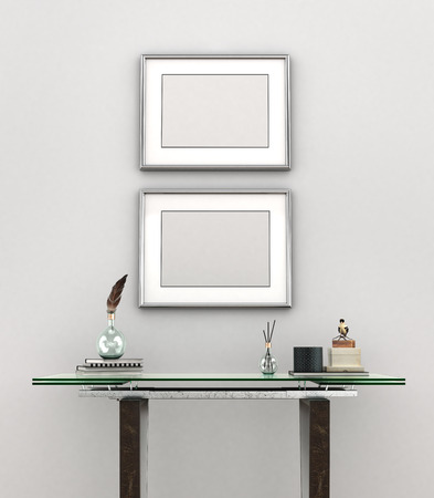 Blank painting with silver frames weigh on a white wall above glass table. 3D illustrationの写真素材