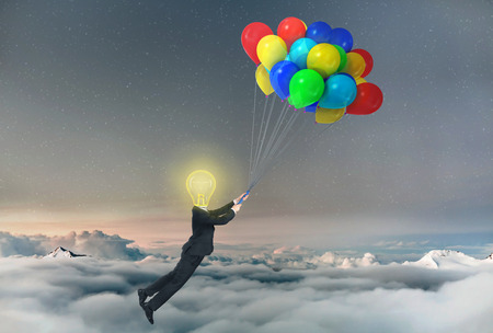 Concept of freedom. A businessman being lifted by balloons with glowing light bulb a head. Concept of idea.の写真素材