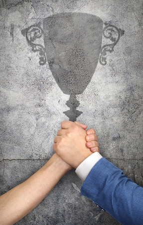 The concept of competition. Fighting hands cast a shadow in the form of a prize cup.の写真素材