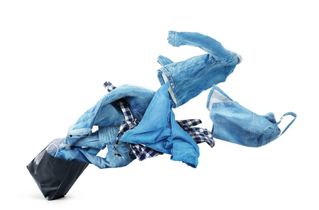 Denim clothes flying out of a black bag isolated on white background. Sale.の写真素材