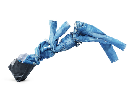 Denim clothes flying out of a black bag isolated on white background. Sale.の写真素材