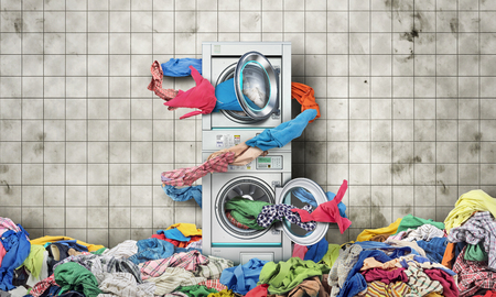 Clothes fly out of a washing machine into a tumble dryerの写真素材