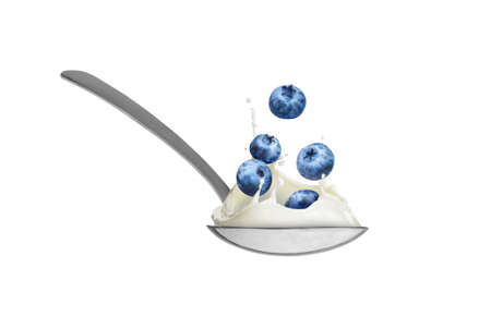 berries with milk in a spoon on a white backgroundの写真素材
