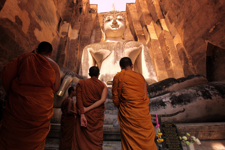 Monks admire the Buddha at Wat Si Chum temple in the temple complex of Old Sukhothai Province Sukhothai in the north of Thailand in South East Asiaのeditorial素材