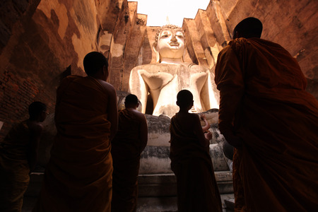 Monks admire the Buddha at Wat Si Chum temple in the temple complex of Old Sukhothai Province Sukhothai in the north of Thailand in South East Asiaのeditorial素材