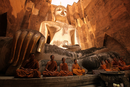 Monks admire the Buddha at Wat Si Chum temple in the temple complex of Old Sukhothai Province Sukhothai in the north of Thailand in South East Asiaのeditorial素材