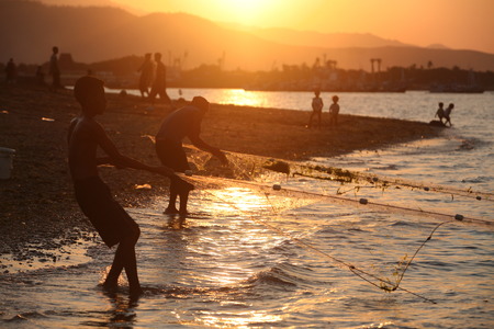Fishermen at Sonnenunteregang on the city beach of Dili the capital of East Timor on the island of Timor separated into two in Asiaのeditorial素材
