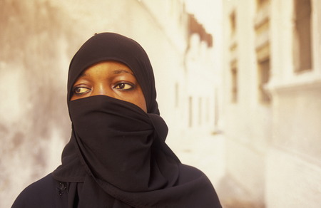 A woman from Zanzibar in traditional dress in the portrait in the middle of Stone Town Zanzibar Town capital on the island of Zanzibar which belongs to Tanzaniaのeditorial素材