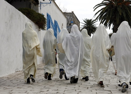 Women in traditional white veil in the old town of Sidi Bou Said in the twilight on the Mediterranean and North of the Tunisian capital, Tunisのeditorial素材