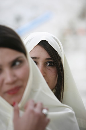 Young women in traditional white veil in the old town of Sidi Bou Said in the twilight on the Mediterranean and North of the Tunisian capital, Tunisのeditorial素材