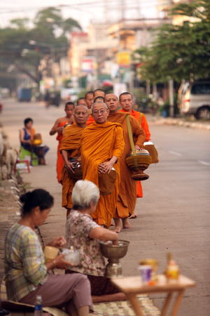 Monks on their tour at the early morning in front of the temple in the city of Tha Khaek in central Laos on the border with Thailand in Southeast Asiaのeditorial素材