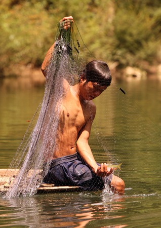 A fisherman in the village of Tha Tham Pa Fa Falang from near the town of Tha Khaek in central Laos on the border with Thailand in Southeast Asia in the countryside at the Nam Don or Don Riverのeditorial素材