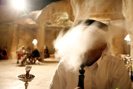 a Men smoking a Waterpipe in a cafe shop in the Village of Wadi Musa near the Temple city of Petra in Jordan in the middle east.のeditorial素材