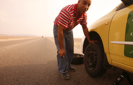 A flat tire on a Taxi on the Desertroad 65 near the Towns Safi and Aqaba in Jordan in the middle east.のeditorial素材