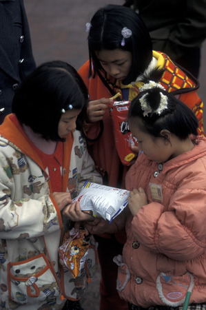 childern with some snaks on the streets of Chongqing in the province of Sichuan in China in east asia.のeditorial素材
