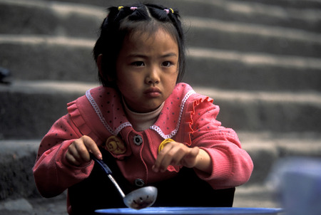a child is cocking at the city of wushan on the yangzee river near the three gorges valley up of the three gorges dam project in the province of hubei in china.のeditorial素材