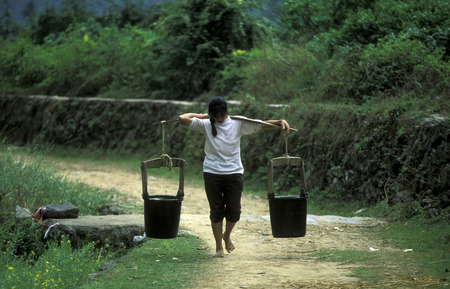 a women with water at the farmland near the town of Yangshou near the city of Guilin in the Guangxi Province of China in in east asia.のeditorial素材