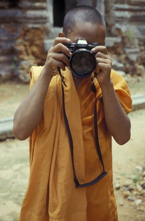 a monk take a pictures at the Bayon temple in Angkor Thom temples in Angkor at the town of Siem Reap in cambodia in Southeastasia.のeditorial素材