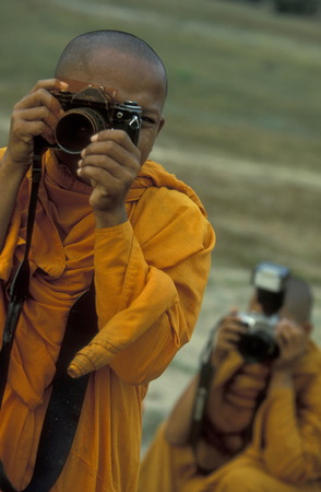 a monk take a pictures at the Bayon temple in Angkor Thom temples in Angkor at the town of Siem Reap in cambodia in Southeastasia.のeditorial素材