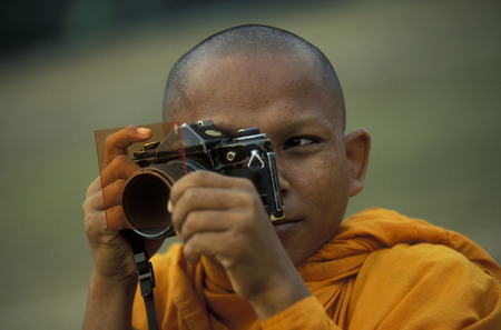 a monk take a pictures at the Bayon temple in Angkor Thom temples in Angkor at the town of Siem Reap in cambodia in Southeastasia.のeditorial素材