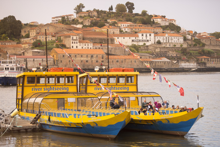 a tourist ship at the waterfront with the old town on the Douro River in Ribeira in the city centre of Porto in Porugal in Europe.のeditorial素材