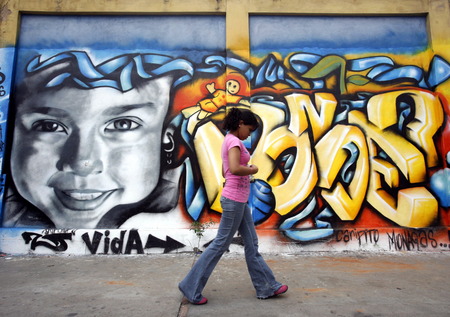 people in a street with graffiti in the city of Valencia in the west of Venezuela.のeditorial素材