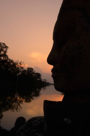 stone face at the Bridge of the south gate to the Angkor Tom city in the Temple City of Angkor near the City of Siem Reap in the west of Cambodia.  Cambodia, Siem Reap, April 2014のeditorial素材