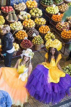 women dressed in colorful clothes at the Mercado dos Lavradores at the Festa da Flor or Spring Flower Festival in the city of Funchal on the Island of Madeira in the Atlantic Ocean of Portugal.  Madeira, Funchal, April, 2018のeditorial素材