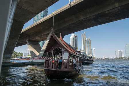 a boat on the chao phraya river and saphan taksin bridge in the city of Bangkok in Thailand in...