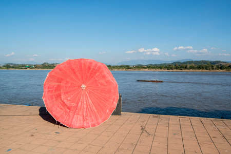 umbrellas of a street food restaurant at the mekong river in the town of Chiang Saen in the north of the city Chiang Rai in North Thailand.   Thailand, Chiang Sean, November, 2019のeditorial素材