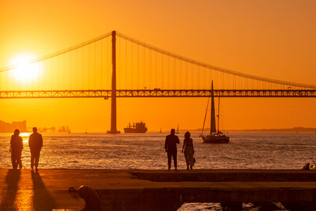 Sailboat with the Ponte 25 de Abril or 25the April Bridge at the Rio Tejo near the City of Lisbon in Portugal.  Portugal, Lisbon, October, 2021のeditorial素材