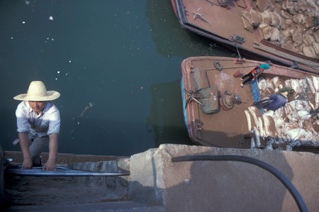 Worker offload Sand for Construction off a Transport ship at the Ganjiang River in the City of Nanchang in the Province of Jiangxi in China. China, Nanchang, November, 1996のeditorial素材