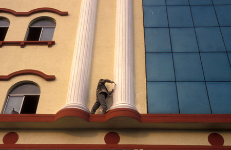 a man painting at a building in the City of Nanchang in the Province of Jiangxi in China. China, Nanchang, November, 1996のeditorial素材