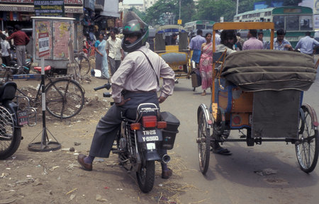 a Riksha Taxi driver waits at his riksha for costumer next to a Motorbike in the city of Chennai in...