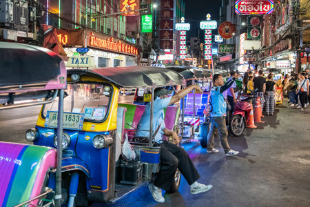People and Tuk Tuk Taxi at Night Streetmarket on Yaowarat Road in Chinatown in City of Bangkok in...