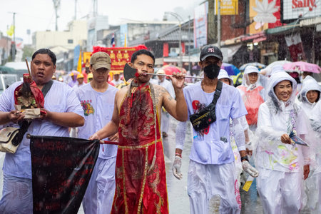 Ma-Song People with face pierced by steel skewers during at spirit ceremony and parade at Phuket...