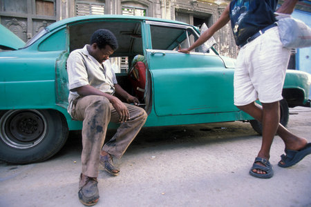 People work on a broken old American car in the city of Havana on Cuba in the Caribbean Sea. Cuba, Havana, October, 2005のeditorial素材