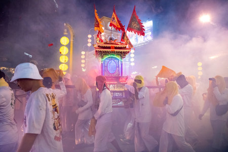 Firecrackers erupt around Devotees which carry a litter housing a Taoist god idol during a spirit...