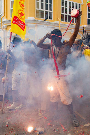 Firecrackers erupt around Devotees which carry a litter housing a Taoist god idol during a spirit...