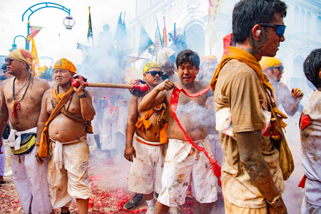 Firecrackers erupt around Devotees which carry a litter housing a Taoist god idol during a spirit...