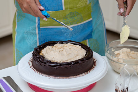 Latin woman applying mouse to a chocolate cake at its beginning