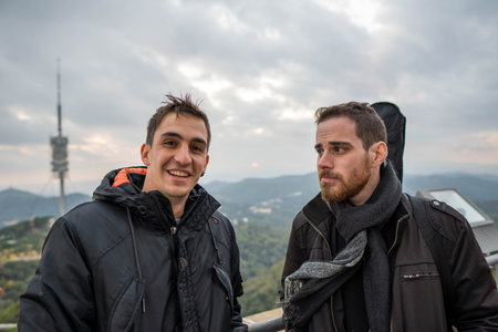 Happy and cool male friends smiling and looking at camera at the city viewpointの写真素材