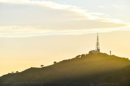 Telecommunications tower on top of a mountain during sunset.