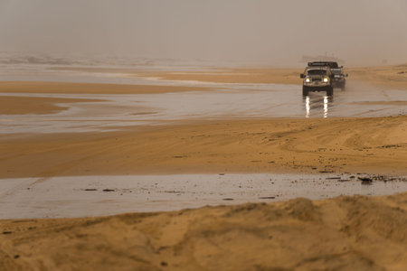 Beach on a day with bad weather with two 4x4 cars in the background. Fraser Island, Queensland,...