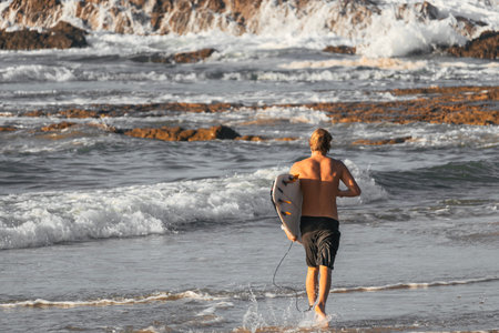Surfer getting into the sea to start surfing at a time of big waves