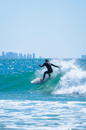 Male surfer riding a wave on a sunny morning on the city beach